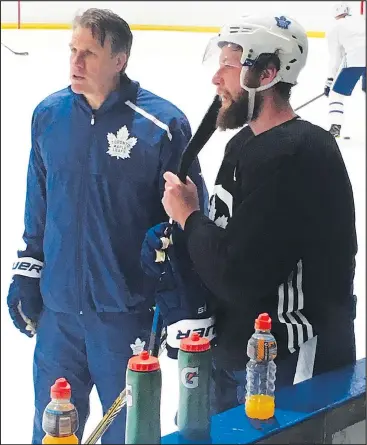  ?? — TERRY KOSHAN/ ?? Leafs assistant coach Jim Hiller (left) talks with newly acquired defenceman Jake Muzzin during a break at practice yesterday.