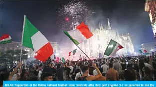  ?? — AFP ?? MILAN: Supporters of the Italian national football team celebrate after Italy beat England 3-2 on penalties to win the Euro 2020 final football match between England and Italy in Piazza del Duomo in Milan on Sunday.