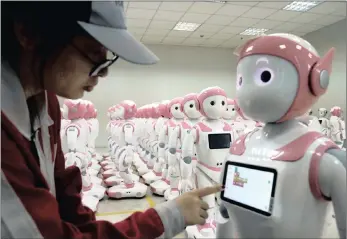  ??  ?? A worker puts finishing touches to an iPal social robot, designed by AvatarMind, at an assembly plant in Suzhou, Jiangsu province, China. Factory output growth has dropped because of a trade war with the US.