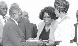  ??  ?? President Mugabe and First Lady Dr Grace Mugabe (right) receive a laptop from Bankers’ Associatio­n of Zimbabwe president Dr Charity Jinya after a meeting with Business at State House yesterday. Picture by John Manzongo