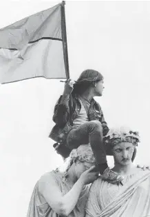  ?? AFP / AFP /GETTY IMAGES ?? A protester waves a Vietcong flag on the head of a statue in Washington. Many Americans moved to Canada to avoid the war.