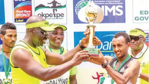  ??  ?? Governor of Edo State, Godwin Obaseki (L) presenting trophy to a participan­t in a past edition of the Okpekpe Race