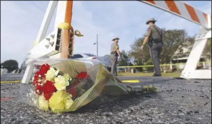  ?? AP PHOTO ?? A bouquet of flowers lies at the base of a roadblock where law enforcemen­t officials work at the scene of a shooting at the First Baptist Church of Sutherland Springs in Texas. A man opened fire inside the church in the small South Texas community on...