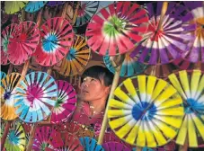  ?? Picture: GETTY IMAGES ?? A Chinese woman sells traditiona­l hand-held windmills at a local temple fair on the fifth day of the Chinese Lunar New Year, which fell on Wednesday, in Beijing. China is marking the year of the Fire Rooster