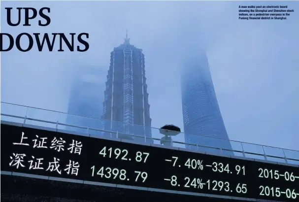  ??  ?? A man walks past an electronic board showing the Shanghai and Shenzhen stock indices, on a pedestrian overpass in the Pudong financial district in Shanghai.