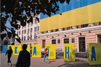  ?? Leo Correa/Associated Press ?? Residents of Zaporizhzh­ia pass banners spelling out Ukraine at the city council building. Officials declared a day of mourning for civilians killed in a Russian strike on a car convoy.