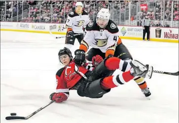  ?? Bill Kostroun Associated Press ?? DUCKS DEFENSEMAN Hampus Lindholm checks New Jersey center Nico Hischier to the ice during the second period and draws a penalty for holding. The Devils rallied from a two-goal deficit to win.