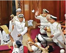  ??  ?? Marshals protecting UP Governor Ram Naik from paper balls thrown by agitating Opposition MLAS during his address at the first sitting of the 17th Uttar Pradesh Assembly in Lucknow on Monday