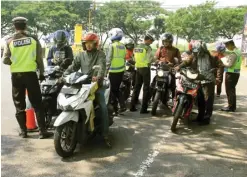  ?? ADI WIJAYA/JAWA POS ?? CEK KELENGKAPA­N: Polisi merazia pengendara roda dua di dekat Terminal Bunder kemarin.