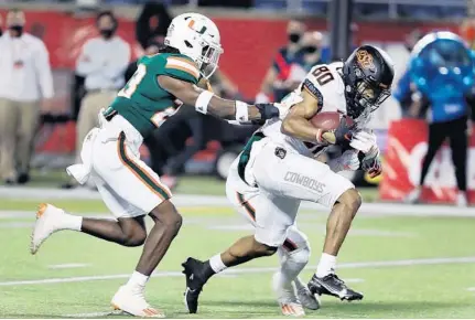  ?? STEPHEN M DOWELL/ ORLANDO SENTINEL ?? Oklahoma State receiver Brennan Presley pulls away from Miami defender Keyshawn Washington for a touchdown during the Cheez-It Bowl at Camping World Stadium in Orlando on Tuesday.