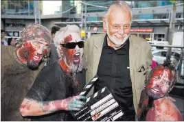  ?? Darren Calabrese ?? The Associated Press George Romero poses with some fans dressed as zombies after accepting a special award during the 2009 Toronto Internatio­nal Film Festival.