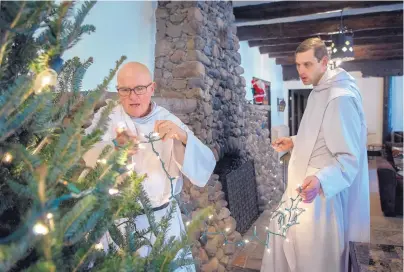  ?? EDDIE MOORE/JOURNAL ?? Brothers Joseph Janeczko, left, and Jacob Kozel string lights on a Christmas tree at Our Lady of Guadalupe Abbey in Pecos. The monks plan to have presents under the tree for children who attend Mass on Christmas Day.