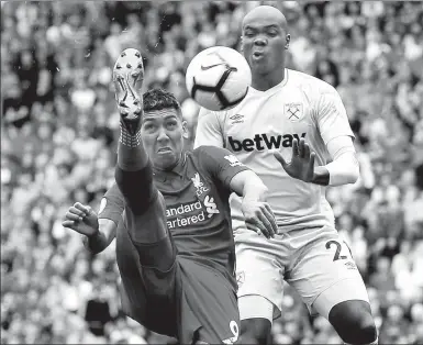  ?? REUTERS ?? Liverpool’s Roberto Firmino beats West Ham United’s Angelo Ogbonna to the ball during Sunday’s English Premier League match at Anfield. The Reds romped to a 4-0 victory.