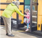  ??  ?? A Brooklyn Park Elementary staff member greets a student getting off a bus Monday.