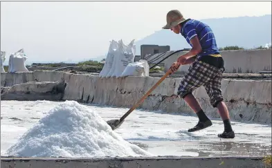  ?? IBRAHIM CHALHOUB / AGENCE FRANCE-PRESSE ?? A worker shovels salt in one of the evaporatio­n ponds located in the Lebanese coastal town of Anfeh on July 21.