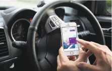  ?? Ore Huiying / Bloomberg 2016 ?? A driver for the Uber Technologi­es demonstrat­es the company’s app on a smartphone in Singapore.