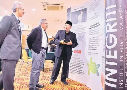  ?? — Gambar Bernama ?? INGIN TAHU: Muhammad Safian (tengah) mendengar penerangan daripada Hamilye (kanan) ketika melawat pameran selepas merasmikan Seminar Pemerkasaa­n Integriti Negeri Pahang, Kuantan semalam.