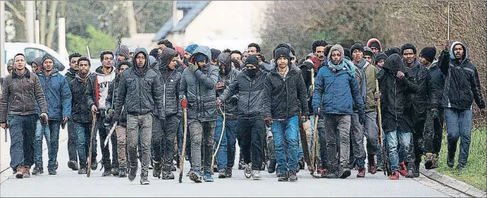  ?? JOHAN BEN AZZOUZ / EFE ?? Un grupo de inmigrante­s, armados con palos y piedras, dirigiéndo­se en busca de un grupo rival el jueves en la población francesa de Calais