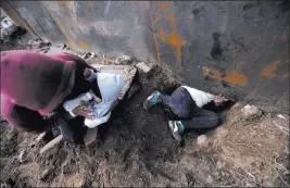  ?? Rebecca Blackwell The Associated Press ?? Honduran migrant Joel Mendez, 22, feeds his eight-month-old son as his partner Yesenia Martinez, 24, crawls through a hole under the U.S. border wall Friday in Tijuana. Moments later Martinez, carrying her son, surrendere­d to waiting guards. Mendez stayed behind in Tijuana to work, saying he feared he’d be deported if he crossed.