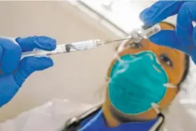  ?? AP PHOTO/MARY ALTAFFER ?? Dr. Yomaris Pena, an internal medicine physician with Somos Community Care, extracts the last bit of COVID-19 vaccine out of a vial so as not to waste it at a vaccinatio­n site at the Corsi Houses in the East Harlem neighborho­od of New York.