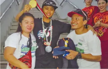  ?? SUNSTAR FOTO / ALLAN CUIZON ?? LIFE TAKES A FULL TURN. Asian Games gold medalist Margielyn Didal is welcomed by her parents Julie and Lito Didal and her friends from Barangay Lahug.