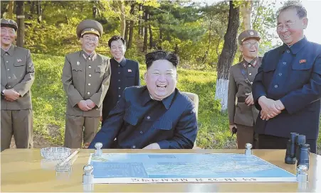  ?? AP PHOTOS ?? LATEST LAUNCH: In an undated photo distribute­d by the North Korean government, North Korean leader Kim Jong Un laughs during the test launch of a missile. At right, Japanese Prime Minister Shinzo Abe speaks to the media regarding today’s test launch of...