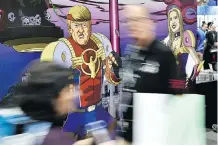  ?? CHRIS PIZZELLO/THE ASSOCIATED PRESS ?? Attendees walk past cut-out figures of U.S. President Donald Trump and his daughter Ivanka at a booth for the satirical comic book series Trump’s Titans.