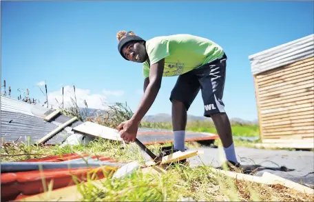  ?? Picture: ARMAND HOUGH ?? RAZED: Luvuyo Mrwetyana packs up parts of what use to be a house. Residents of the wetlands area in Masiphumel­ele have been evicted from their houses and told that their belongings will be confiscate­d if they try to rebuild it.