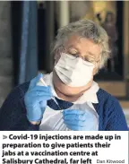  ?? Dan Kitwood ?? > Covid-19 injections are made up in preparatio­n to give patients their jabs at a vaccinatio­n centre at Salisbury Cathedral, far left