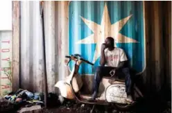  ??  ?? A Malian man sits on the chassis of an old Vespa.