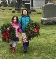  ?? SUBMITTED PHOTO ?? Madison Catagnus, left, and Abigail Catagnus carry wreaths to be placed on the tombstones of veterans during the Wreaths Across America event held at St. James Episcopal Church on Germantown Pike in Collegevil­le on Dec. 15.