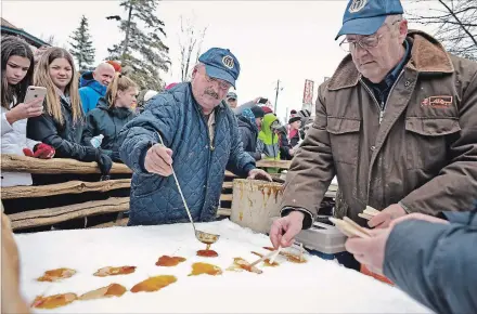  ?? IAN STEWART SPECIAL TO THE RECORD ?? Steve Bisbee pours syrup on snow to make maple taffy , as Steve Martin places the sticks at the Elmira Maple Syrup Festival on Saturday.