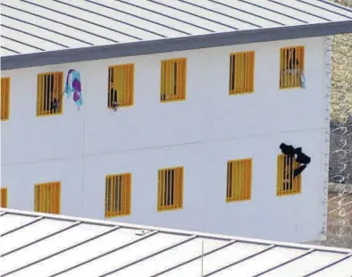  ?? DIARIO DE TERUEL ?? (( Unos reclusos de la prisión de Teruel se asoman por las ventanas de sus celdas durante el confinamie­nto.