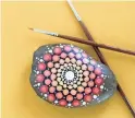 ??  ?? This colorfully-painted mandala stone was made with a paintbrush.