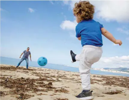  ?? — AFP ?? A child plays footbal with his father at Can Pere Antoni Beach in Palma de Mallorca, on Sunday during a national lockdown to prevent the spread of the COVID-19 disease. After six weeks stuck at home, Spain’s children were being allowed out today to run, play or go for a walk as the government eased one of the world’s toughest coronaviru­s lockdowns.