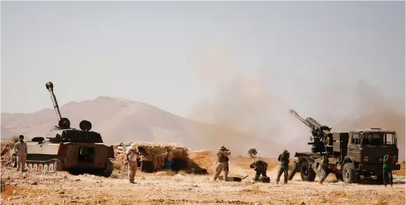  ?? (Reuters) ?? HEZBOLLAH FIGHTERS stand near military tanks in Western Qalamoun, Syria.