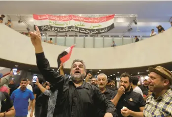  ?? ANMAR KHALIL/AP ?? Iraqi protesters pose with national flags inside the parliament building Sunday in Baghdad, Iraq. Thousands of followers of an influentia­l Shiite cleric stormed into Iraq’s parliament Saturday, for the second time in a week, protesting government formation efforts led by his rivals, an alliance of Iran-backed groups.