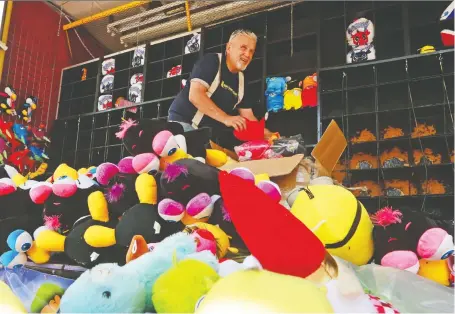  ?? GAVIN YOUNG ?? North American Midway Entertainm­ent worker John Heyward loads prizes into a booth in preparatio­n for the opening of Stampede.