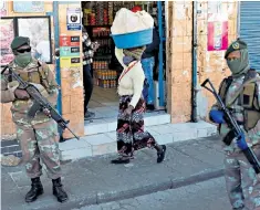  ??  ?? Soldiers keep watch outside a store as lockdown restrictio­ns are eased