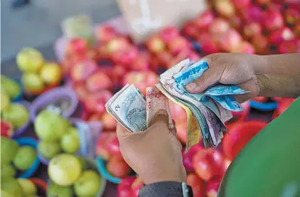  ?? AP ?? Billetes. Un hombre busca cambio para comprar fruta en un mercado carioca. Los precios se dispararon.