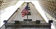  ?? RICHARD DREW — THE ASSOCIATED PRESS FILE ?? In this photo, the American flag flies above the Wall Street entrance to the New York Stock Exchange. Stocks were moving mostly lower in early trading Monday as investors looked ahead to the Fed’s meeting in Jackson Hole, Wyo., for clues on timing for...