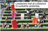  ??  ?? Londoners met at a distance to sunbathe yesterday