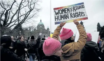  ?? CHAD HIPOLITO/THE CANADIAN PRESS ?? People hold signs as they make their way to the Legislatur­e during the Women’s March in Victoria, B.C., on Saturday.