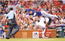  ??  ?? The Toronto Blue Jays’ Chris Coghlan, top, leaps over St. Louis Cardinals catcher Yadier Molina to score during the seventh inning of their April 25 game in St. Louis. Coghlan somehow landed on the plate, and the Blue Jays took a 3-2 lead.