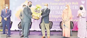  ??  ?? PPNS Gulamhaida­r presenting a basket of Hari Raya cookies to Hajiji.