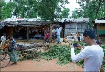  ??  ?? Rafiq (right) uses his mobile phone to take photos at the Kutupalong refugee camp.