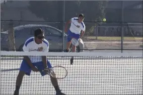  ?? KARINA LOPEZ PHOTO ?? Brawley Union High School's Jerry Esquer (background) serves the ball as teammate Richard Mortimer looks on during a home tennis match against Vincent Memorial last season. Both Mortimer and Esquer earned All-Imperial Valley League honors this season.