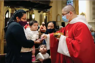  ?? AP-Jessie Wardarski ?? Parishione­rs receive the sacrament from the Rev. Luis Gabriel Medina during Communion at Saint Bartholome­w Roman Catholic Church in the Queens borough of New York, on July 6. This was the first in-person Mass at the church in almost four months.