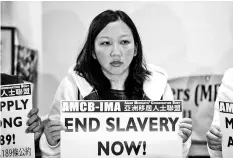  ??  ?? Sulistyani­ngsih holds a sign that reads ‘End Slavery Now’ during a press conference in Hong Kong. — AFP photo