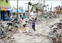  ?? DOUGLAS R. CLIFFORD — TAMPS BAY TIMES ?? Jake Moses, 19, left, and Heather Jones, 18, of Fort Myers, Fla., explore a section of destroyed businesses at Fort Myers Beach. The community was mostly destroyed after Hurricane Ian made landfall Sept. 28.